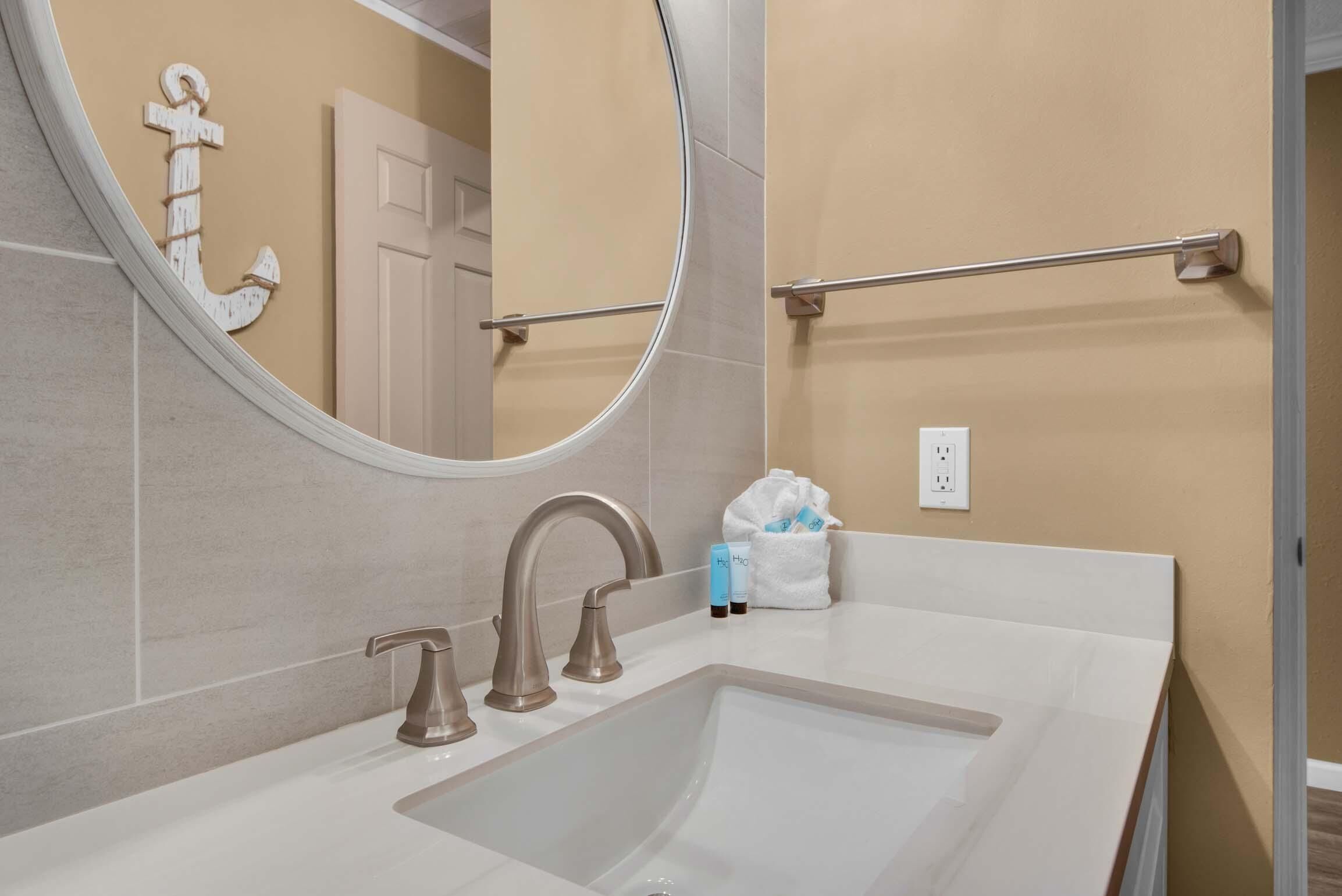 A bathroom with a large mirror, a sink with two faucets, and a towel rack.