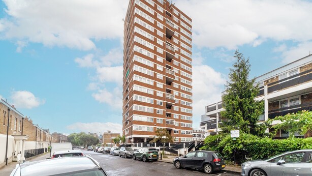Un grand immeuble résidentiel à plusieurs étages, doté d’une façade en briques et de nombreuses fenêtres.