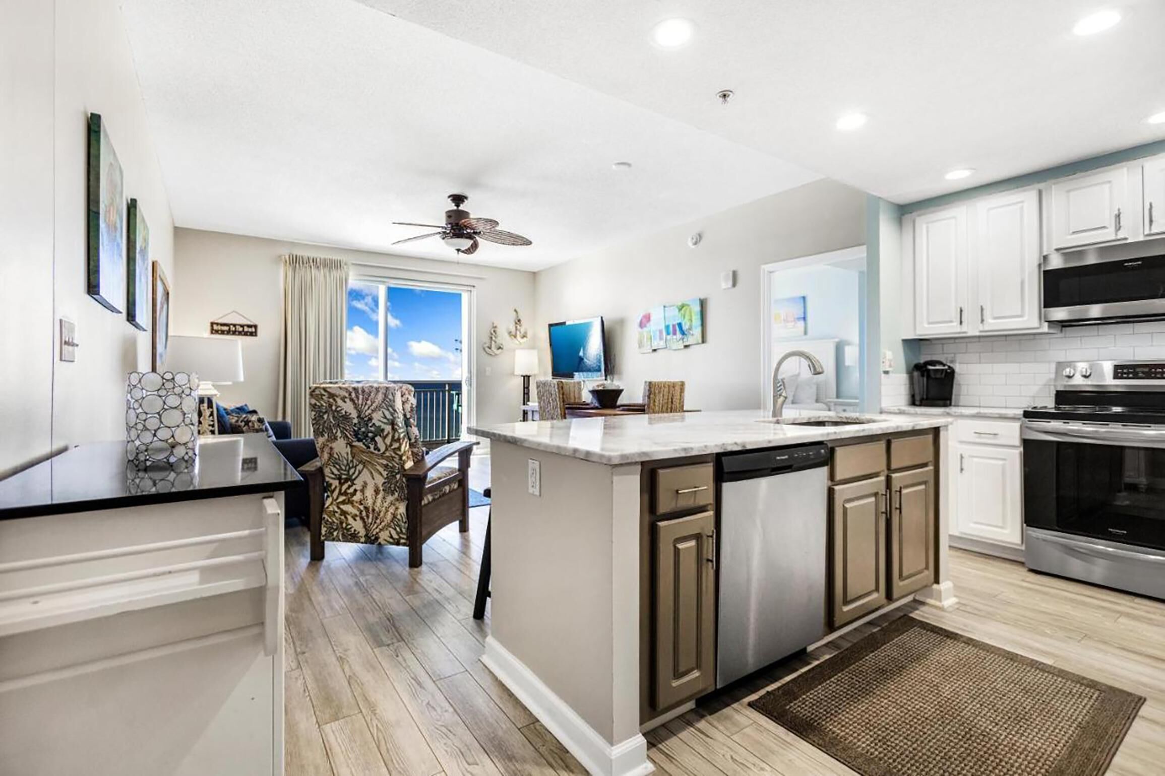 A modern kitchen with a large island, stainless steel appliances, and a ceiling fan.