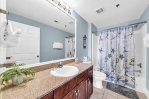 Bathroom features a large mirror, granite countertop sink, and a shower curtain with a nautical theme.