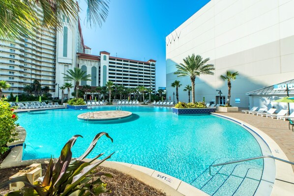 Relax by the pool surrounded by palm trees and lounge chairs.