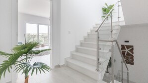 A modern interior with a white staircase, large windows, and indoor plants. - Villa Bela Vista, beach villa with ocean view  (Atalaia)