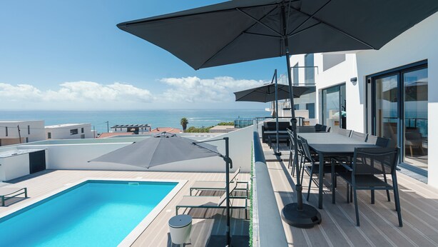 A rooftop pool area with a view of the sea, outdoor seating, and umbrellas. - Villa Bela Vista, beach villa with ocean view  (Atalaia)