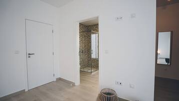 Contemporary bathroom with a patterned shower area, complemented by a natural wicker basket and a mirror.