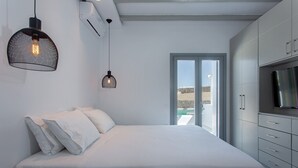 Ein modernes Schlafzimmer mit einem großen Bett, weißer Bettwäsche und zwei Pendelleuchten.