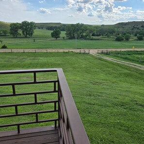 A grassy field with a fence and a road in the distance.