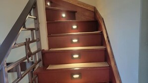 A wooden staircase with metal railings and illuminated steps. - Canyon Acres Ranch • Horse-Friendly Kansas Retreat (Russell)