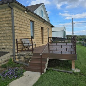 A brick building with a wooden deck, a window, and a door. - Canyon Acres Ranch • Horse-Friendly Kansas Retreat (Russell)