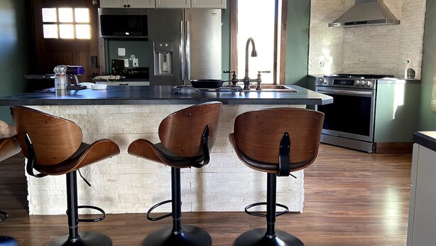 A modern kitchen with a central island, bar stools, and stainless steel appliances. - Canyon Acres Ranch • Horse-Friendly Kansas Retreat (Russell)
