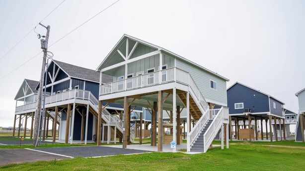 A coastal residential area with multiple two-story houses featuring balconies, wooden decks, and a grassy front yard. - Charming 2-bedroom house in Wonderful Bolivar Peninsula with AC, WiFi (Bolivar Peninsula)