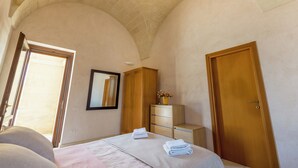 Ein Schlafzimmer mit einem Bett, einem Holzschrank, einem Spiegel und einer Tür.