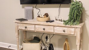 Una consola de madera con un televisor de pantalla plana montado encima, cajones, una cesta y una pequeña planta.