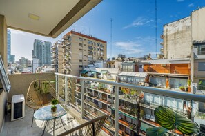 A balcony with a glass table, a chair, and potted plants. -  MOT Paunero (Buenos Aires)