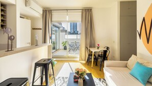 En modern lägenhet med kök, matplats och vardagsrum med soffa och soffbord.