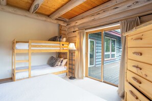 A bunk bed room with a wooden dresser and a lamp.