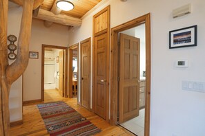 A hallway with wooden doors, a patterned rug, and a ceiling light fixture.