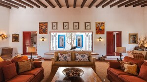 A cozy living room with a wooden ceiling, a large window with blue shutters, and a fireplace. - Charming Farm House With Pool (Ferreira do Alentejo)