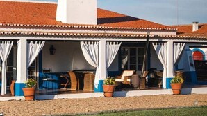 A building with a white chimney, a red-tiled roof, and a covered patio area with outdoor seating. - Charming Farm House With Pool (Ferreira do Alentejo)