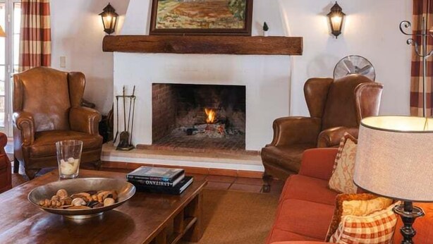 A cozy living room with a fireplace, wooden beams, leather chairs, and a sofa. - Charming Farm House With Pool (Ferreira do Alentejo)