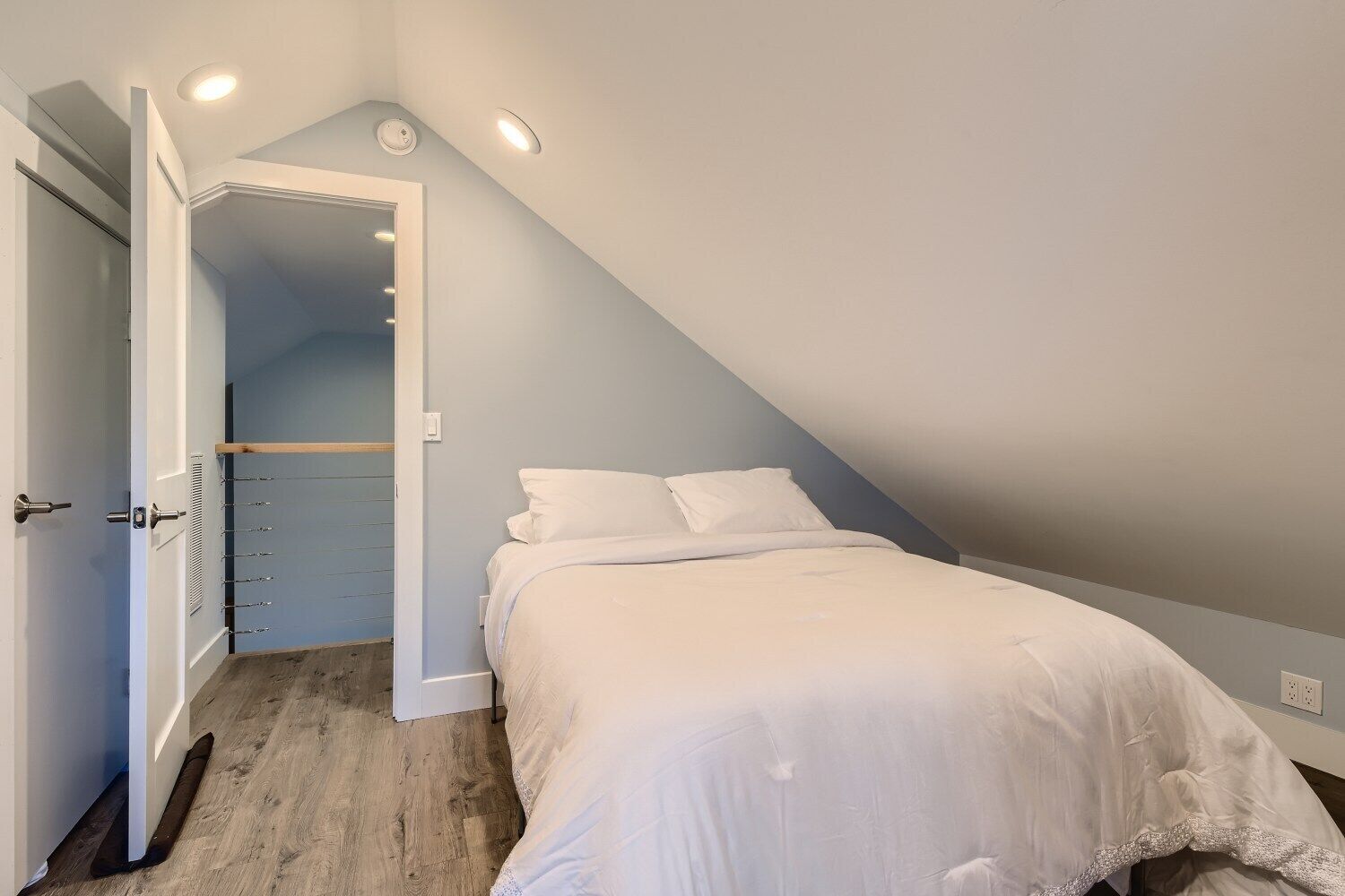 Un dormitorio con cama, una puerta que da a un armario y techo inclinado.