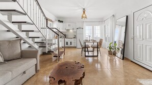 Eine moderne Küche mit weißen Schränken, ein Essbereich mit Holztisch und eine Treppe mit Metallgeländer.
