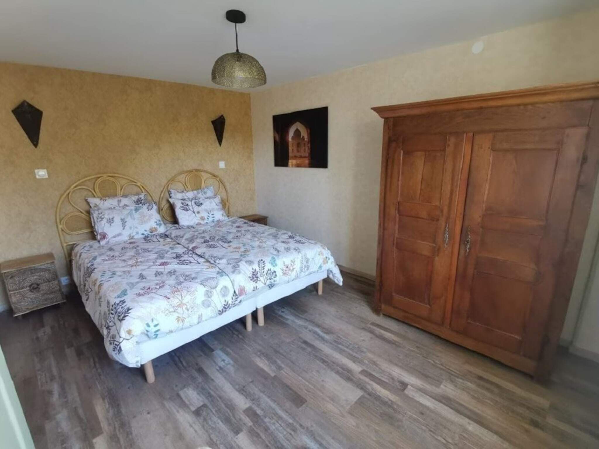Une chambre à coucher avec un lit, une armoire en bois et un tableau accroché au mur.