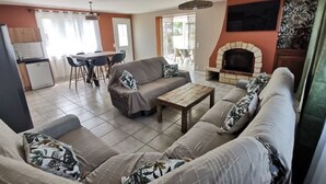 Una sala de estar con un conjunto de sofá, una mesa de centro y una chimenea. Hay un comedor con sillas y una mesa.