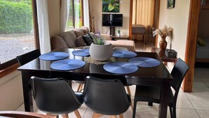 Un coin repas avec une table en bois foncé, des sets de table bleus et des chaises noires.