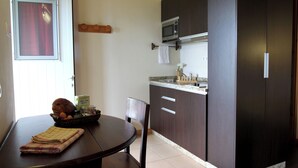 A compact kitchen with dark wooden cabinets, a microwave, and a small countertop. - Casa Avó Filomena West (Santo Amaro)