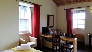 A room with a bed, a desk with a computer, a chair, a sofa, and a window with red curtains. - Casa Avó Filomena West (Santo Amaro)