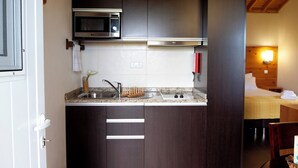 A compact kitchen with dark cabinetry, a microwave, a sink, and a countertop. - Casa Avó Filomena West (Santo Amaro)