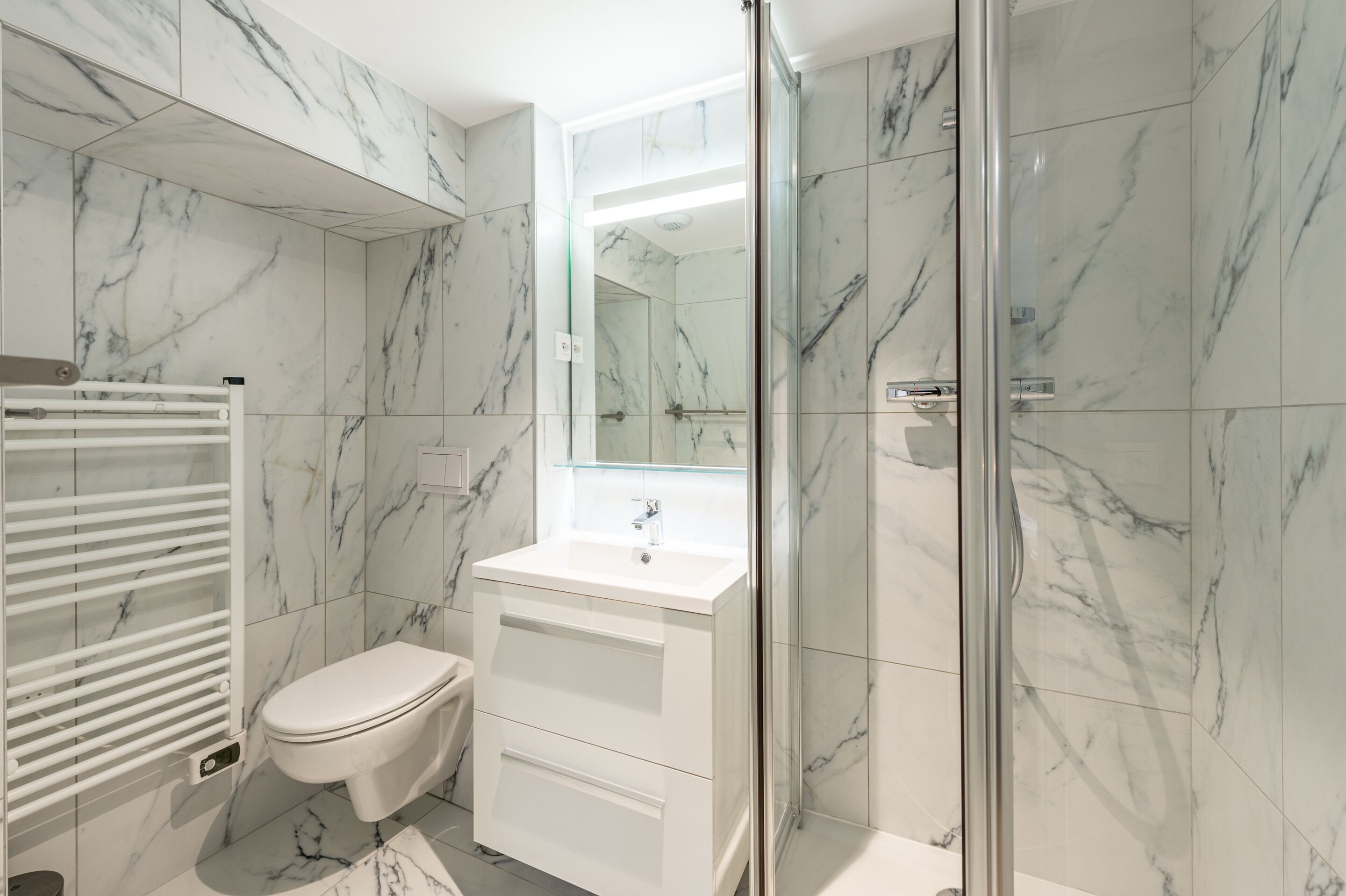A bathroom with a white toilet, a sink, and a glass shower enclosure.