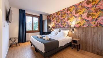 A modern hotel room with a large bed, a wooden headboard, a wall-mounted TV, and a window with curtains.