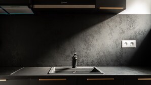 A modern kitchen with dark cabinetry, a stainless steel range hood, and a built-in oven. - Les Tonnelles (Sevrier)