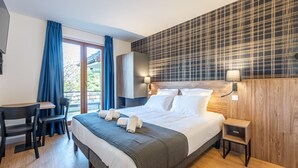 A modern hotel room with a large bed, a desk, and a view of the outdoors. - Les Tonnelles (Sevrier)