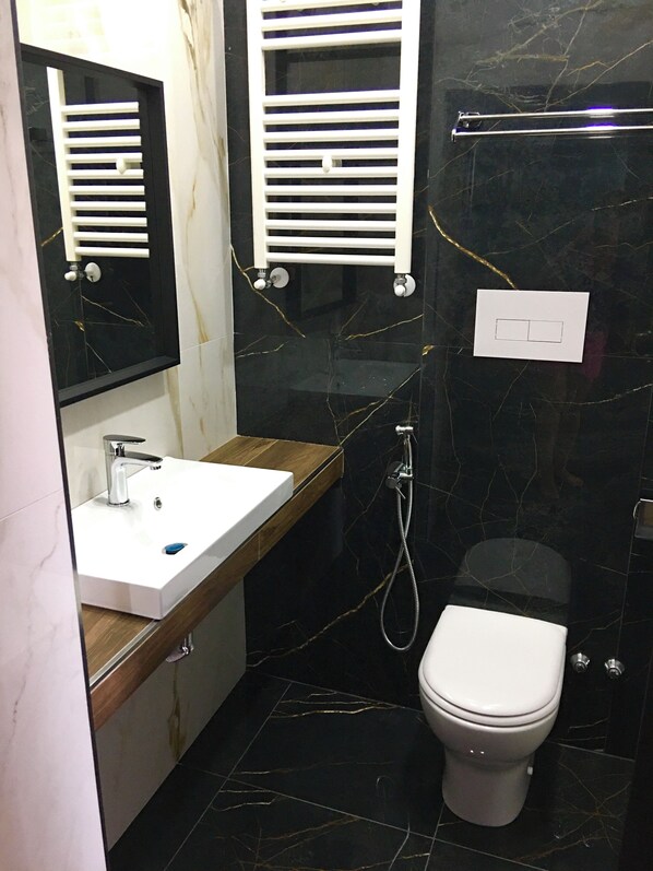 A modern bathroom with a white sink, mirror, and toilet. - Katarios Suite (Naples)