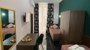 Une chambre d’hôtel de taille réduite, comprenant un lit, un bureau avec une chaise, une armoire et un miroir.