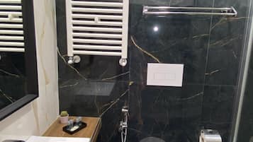 Une salle de bain moderne avec un lavabo, des toilettes et une douche, le tout de couleur blanche.