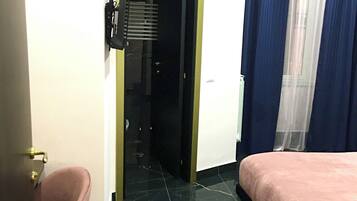 Una camera d'albergo con un letto, una sedia, una porta e una finestra con tende.