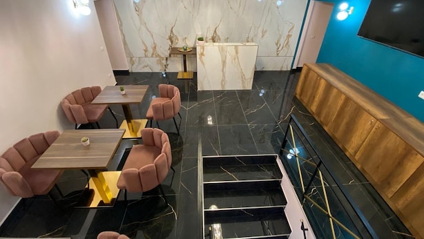 Un intérieur moderne avec un mur en marbre, un comptoir d’accueil, un escalier et un téléviseur à écran plat.
