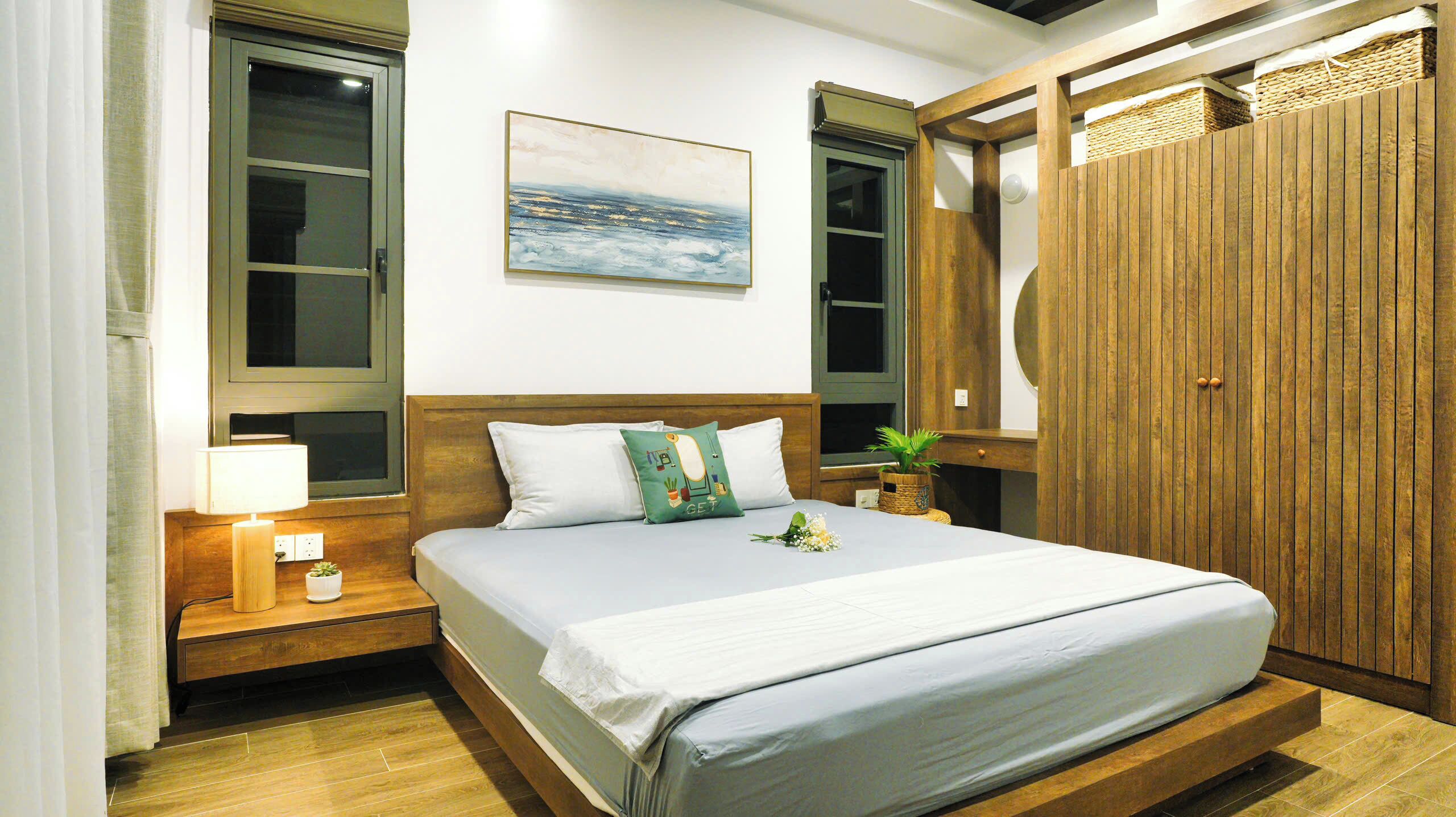 Un dormitorio ordenado con una cama grande, cabecera de madera, un cuadro sobre la cama y un armario de madera.