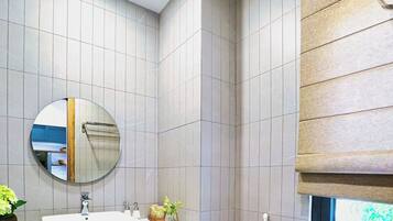 Een moderne badkamer met een wit wastafel, houten wastafelmeubel, een ronde spiegel en een toilet.