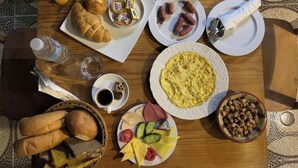 A breakfast table with croissants, sausages, eggs, and various fruits and cheeses. - Amadeus familias (Giza)