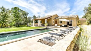 A house with a swimming pool, outdoor seating, and a covered patio area.