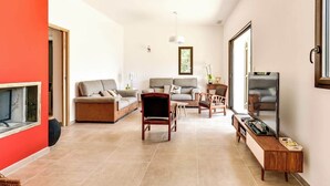 A modern living room with a sofa, chairs, a coffee table, and a TV.