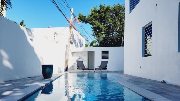 A modern swimming pool with two lounge chairs and a trash bin. - WE HAVE WATER!! Pool Mansion walk to Beach, sleeps 30+guests (San Juan)