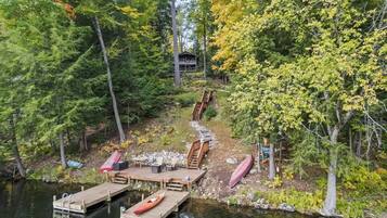 A cabin surrounded by dense forest, accessible by a wooden staircase.