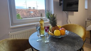 A dining area with a table set for two, a bottle of wine, two glasses, and a fruit bowl. - Charming studio in Zagreb with AC, fitness room, WiFi and spa zone  (Zagreb)