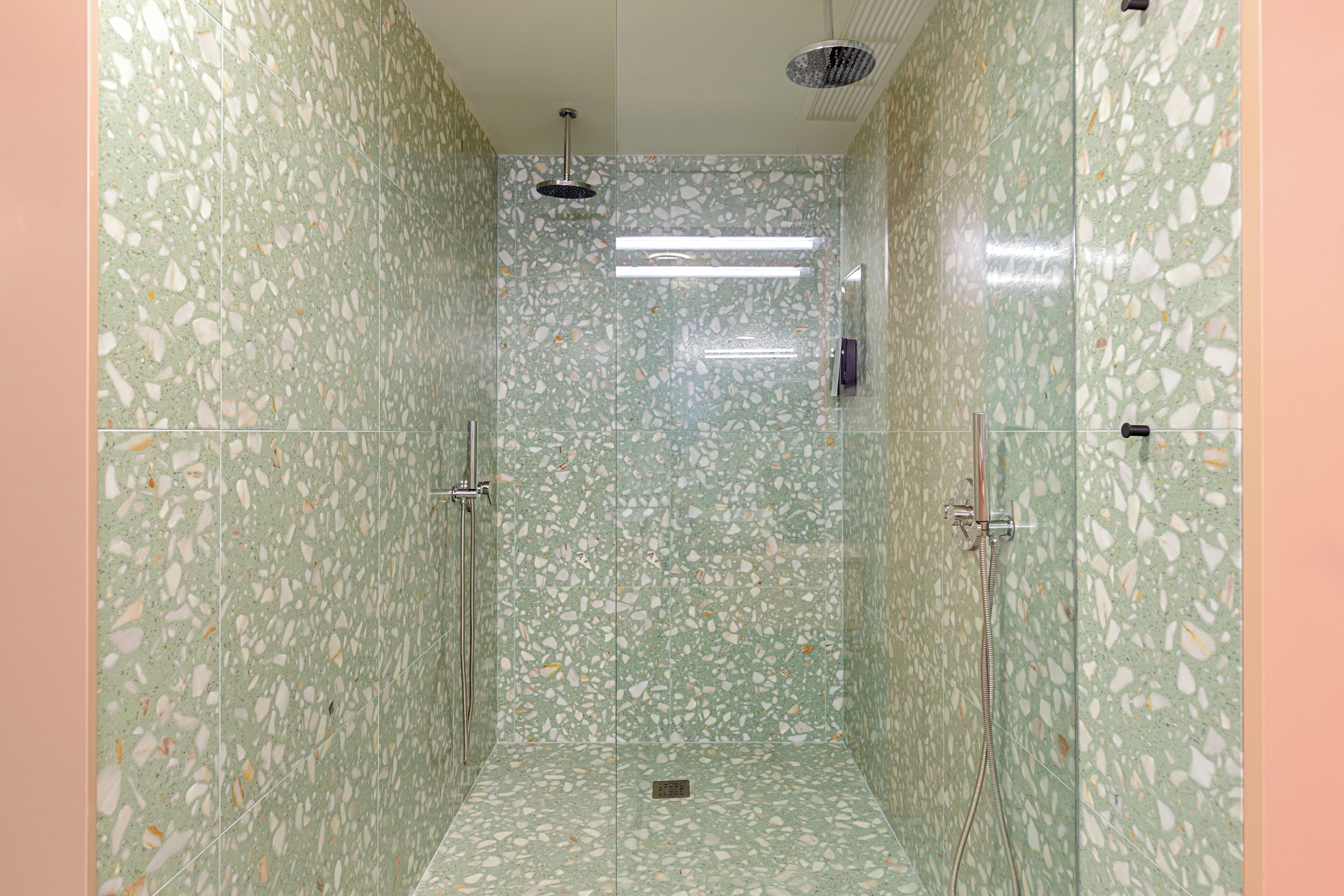A shower with terrazzo walls and a glass door.