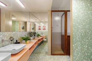 A modern bathroom with two sinks, a mirror, and a shower area. - Pelicano (Porto)